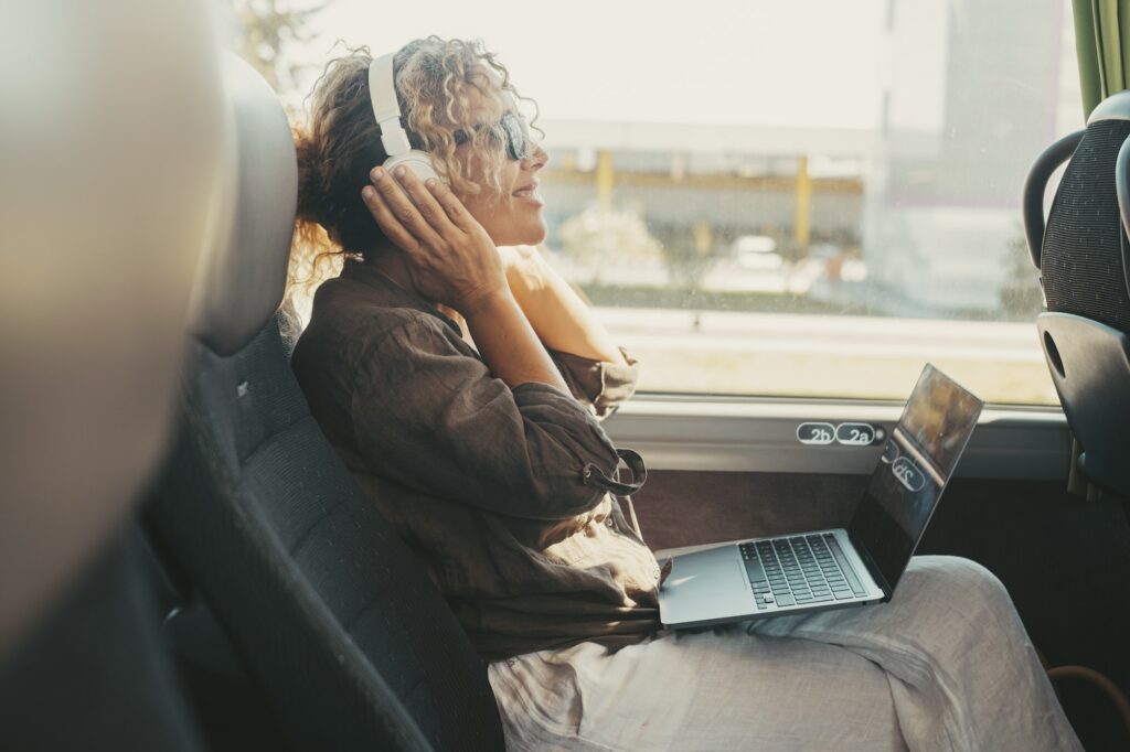 One woman listening music with headphones and computer sitting inside public bus transport